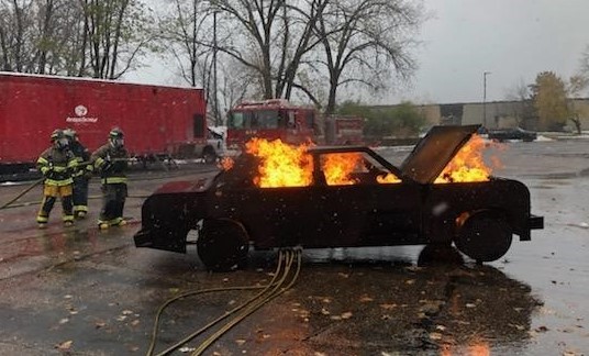 2 fire fighters with hose trying to put out vehicle fire